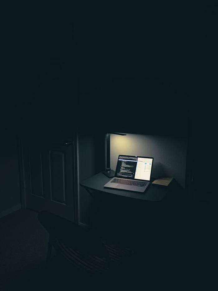 Notebook aberto sobre uma mesa iluminada por luminária